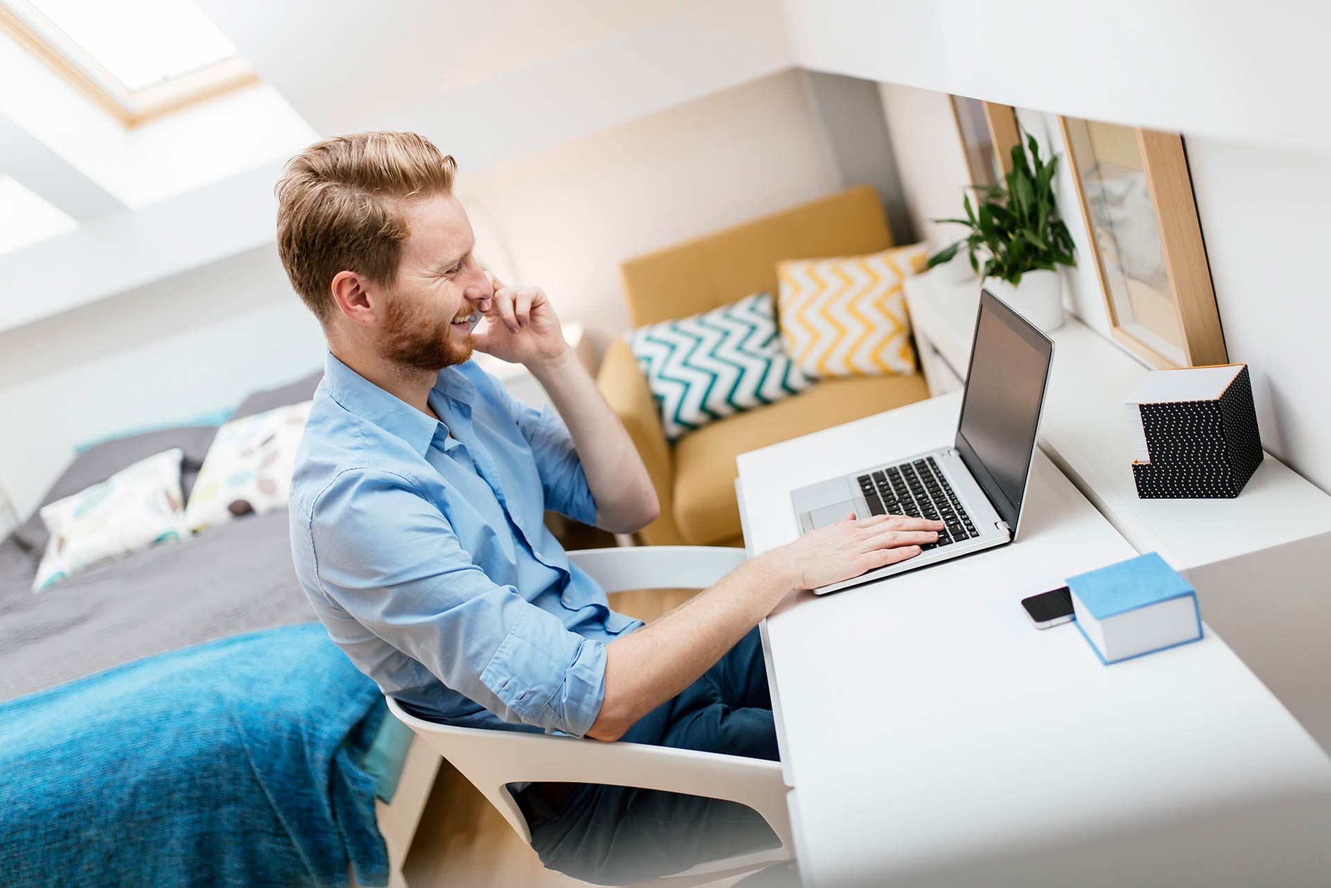 man smiling on the phone while working on laptop