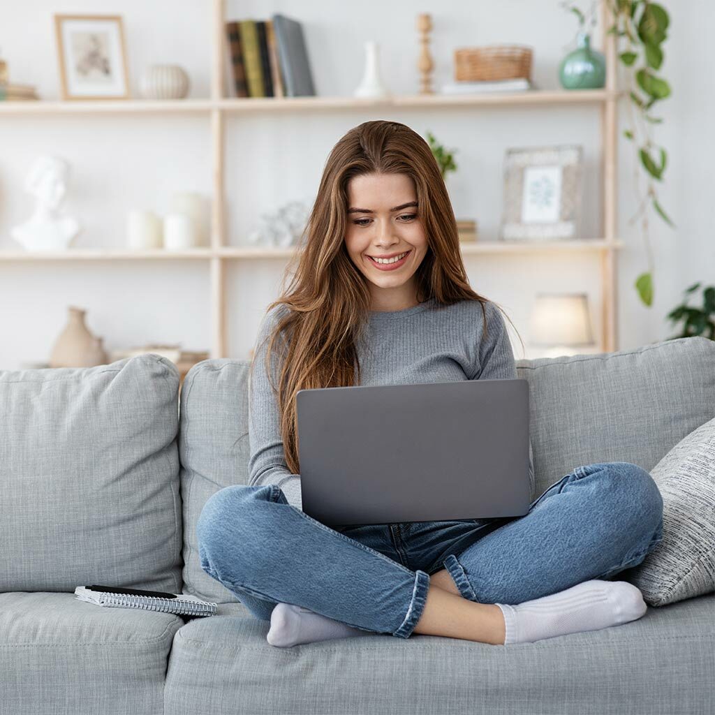 woman smiling working from home using her laptop